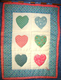 small wall hanging quilt with 6 small hearts